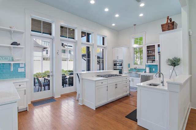 kitchen with sink, white cabinetry, tasteful backsplash, light hardwood / wood-style flooring, and stainless steel appliances