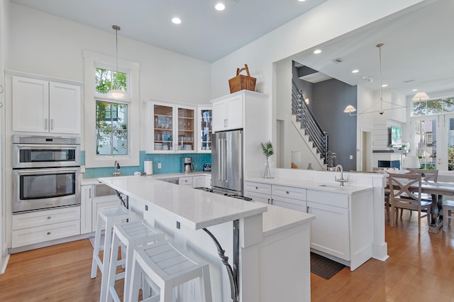 kitchen with pendant lighting, appliances with stainless steel finishes, a center island, white cabinets, and kitchen peninsula