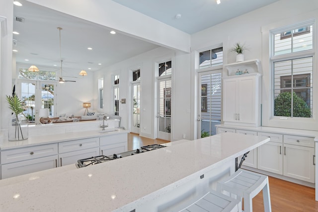 kitchen with white cabinetry, light stone countertops, a wealth of natural light, and a kitchen breakfast bar