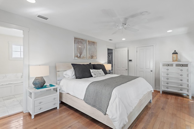 bedroom with ensuite bathroom, wood-type flooring, ceiling fan, and a closet