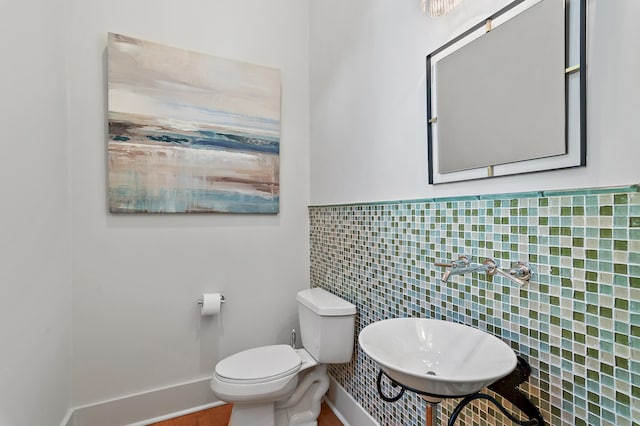 bathroom featuring sink, tile walls, and toilet