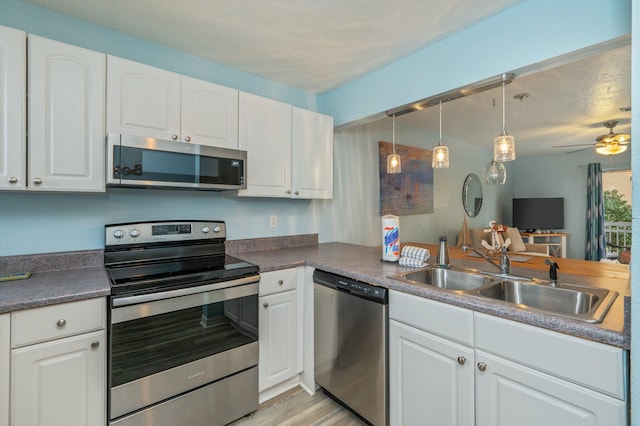 kitchen with sink, kitchen peninsula, white cabinets, and appliances with stainless steel finishes