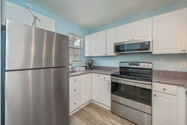 kitchen with stainless steel appliances, white cabinets, and light wood-type flooring