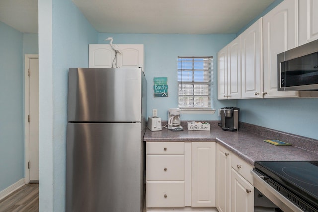 kitchen with hardwood / wood-style flooring, appliances with stainless steel finishes, and white cabinets