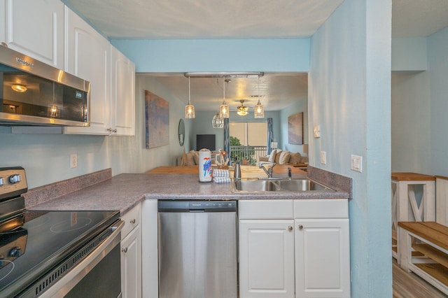 kitchen featuring white cabinetry, sink, hanging light fixtures, kitchen peninsula, and stainless steel appliances