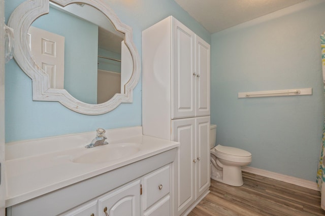 bathroom with wood-type flooring, toilet, and vanity