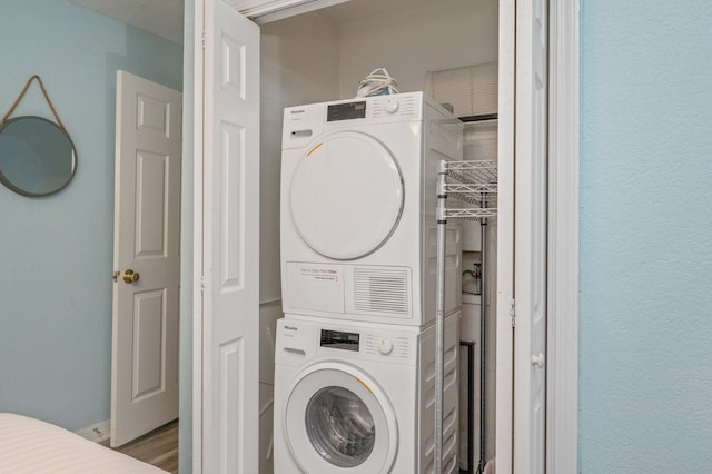 washroom featuring hardwood / wood-style flooring and stacked washer / dryer