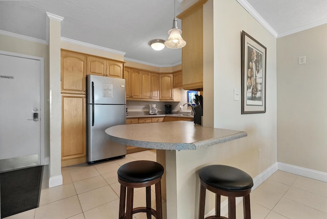 kitchen with stainless steel refrigerator, crown molding, a breakfast bar, and light tile patterned flooring