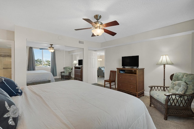 carpeted bedroom with ceiling fan, a closet, and a textured ceiling