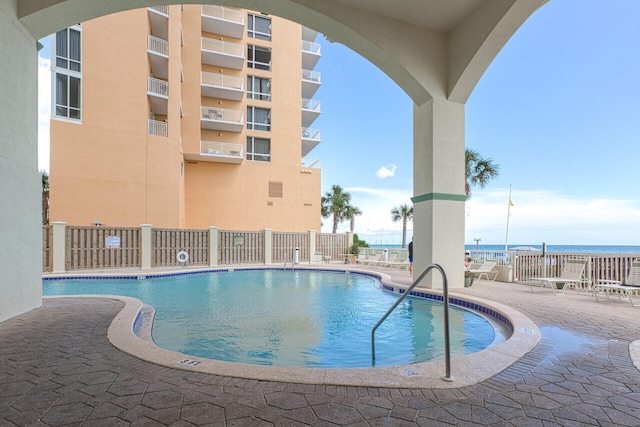 view of swimming pool featuring a water view and a patio