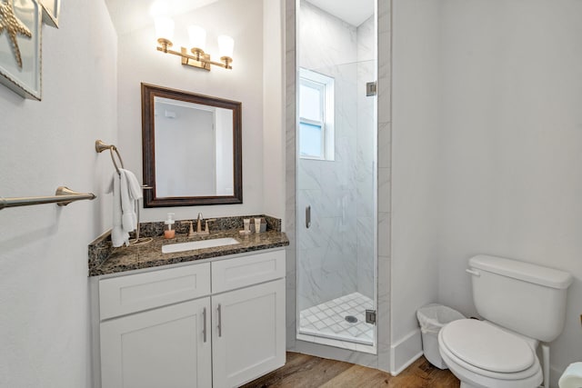 bathroom featuring vanity, hardwood / wood-style flooring, a shower with door, and toilet