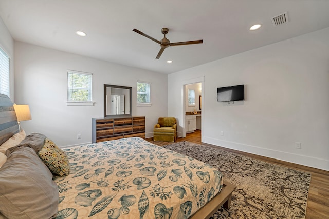 bedroom featuring ceiling fan, hardwood / wood-style flooring, multiple windows, and ensuite bath