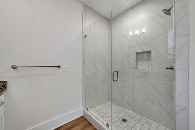 bathroom with hardwood / wood-style flooring, a shower with door, and vanity