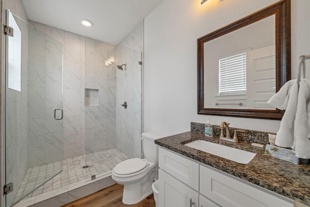 bathroom with vanity, toilet, an enclosed shower, and wood-type flooring