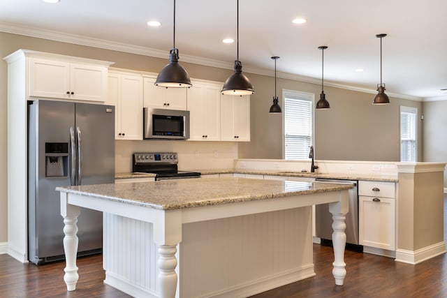 kitchen with white cabinets, pendant lighting, a center island, and appliances with stainless steel finishes