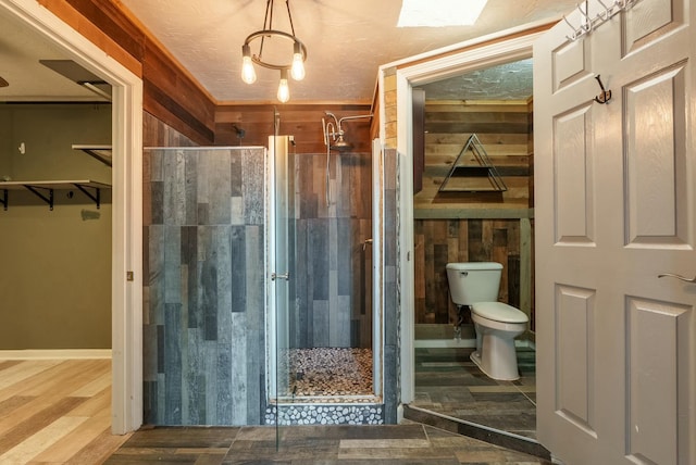 bathroom featuring wooden walls, a shower with door, and toilet