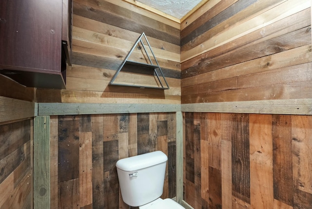 bathroom with toilet and wood walls