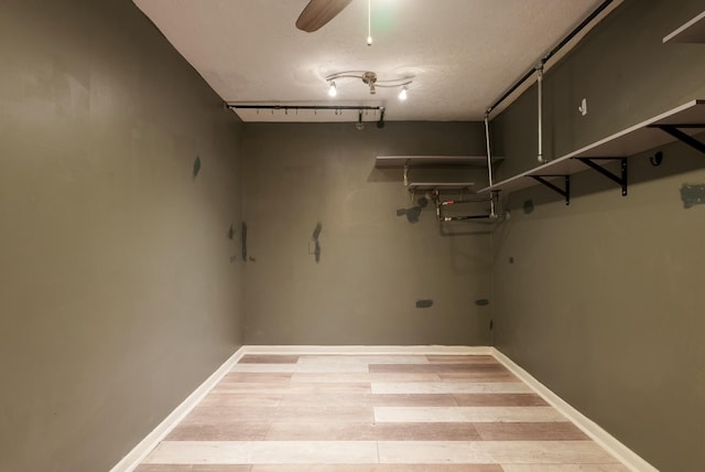 basement with rail lighting, a textured ceiling, and ceiling fan