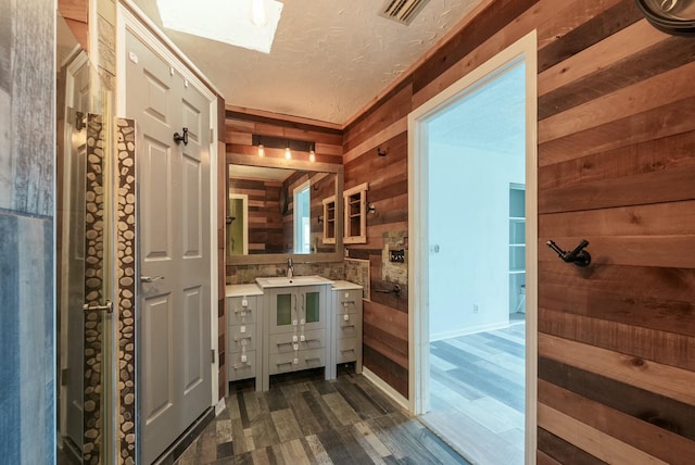 bathroom with vanity, wooden walls, and a textured ceiling