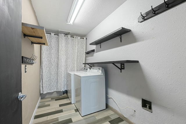 clothes washing area with separate washer and dryer, a textured ceiling, and light hardwood / wood-style floors