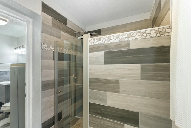 bathroom featuring toilet, tiled shower, and a textured ceiling