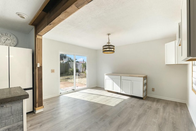 unfurnished dining area with light hardwood / wood-style flooring and a textured ceiling