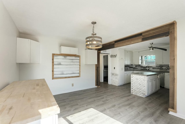 kitchen with dishwasher, wood-type flooring, white cabinetry, sink, and hanging light fixtures