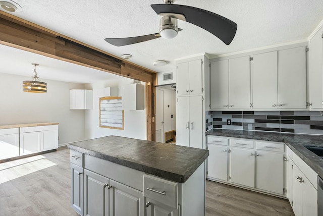 kitchen with backsplash, white cabinetry, light wood-type flooring, and ceiling fan