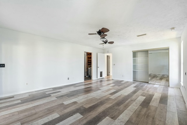 empty room featuring ceiling fan, light hardwood / wood-style flooring, and a textured ceiling