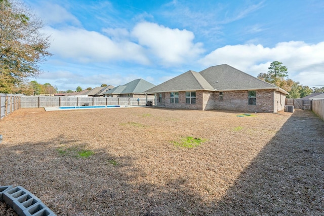 back of property with an empty pool and a lawn