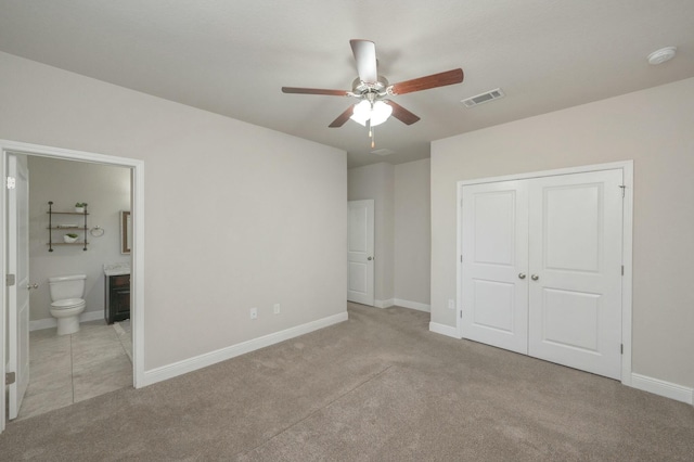 unfurnished bedroom featuring ceiling fan, a closet, ensuite bathroom, and light carpet