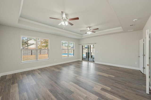 spare room with crown molding, a tray ceiling, and dark wood-type flooring