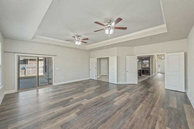 unfurnished living room with a raised ceiling, crown molding, dark hardwood / wood-style floors, and ceiling fan