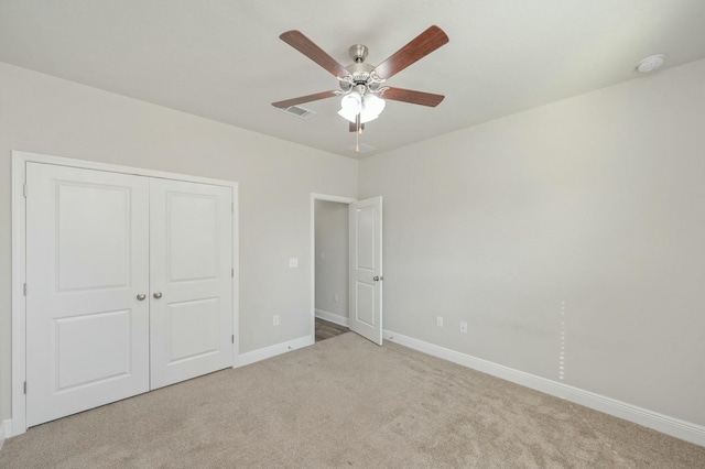 unfurnished bedroom featuring light carpet, a closet, and ceiling fan