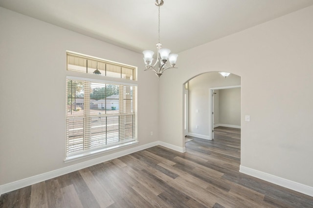 empty room featuring an inviting chandelier and dark wood-type flooring