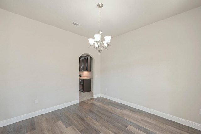 spare room with wood-type flooring and a chandelier