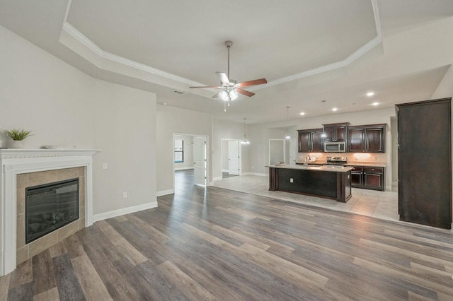 kitchen featuring dark brown cabinetry, a raised ceiling, and an island with sink