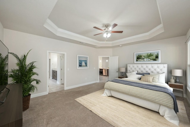 carpeted bedroom with crown molding, connected bathroom, a tray ceiling, and ceiling fan