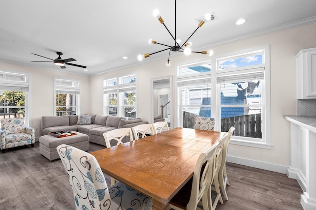 dining area featuring ceiling fan with notable chandelier, dark wood-type flooring, and ornamental molding