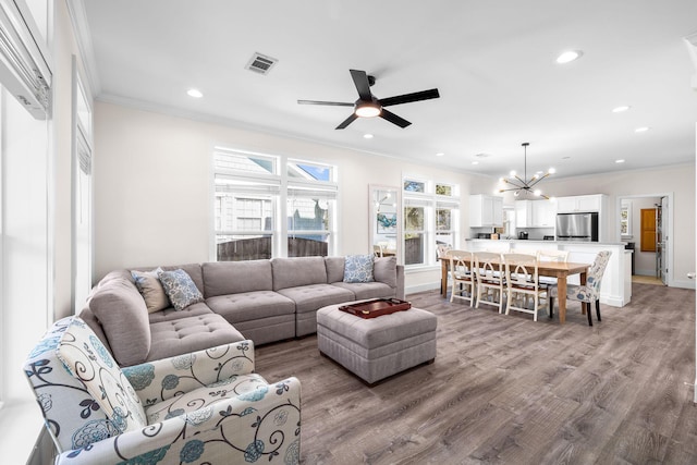 living room with crown molding, ceiling fan with notable chandelier, and light wood-type flooring