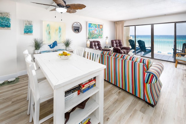 dining area featuring a water view, ceiling fan, and light hardwood / wood-style flooring