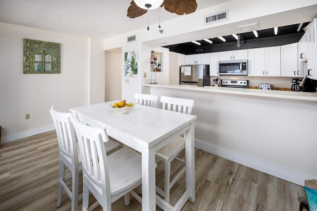 dining room with ceiling fan, a textured ceiling, and light wood-type flooring