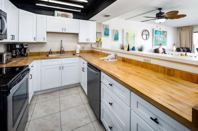 kitchen with wood counters, sink, stainless steel appliances, and kitchen peninsula