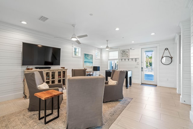 living room with ceiling fan, ornamental molding, and light tile patterned floors