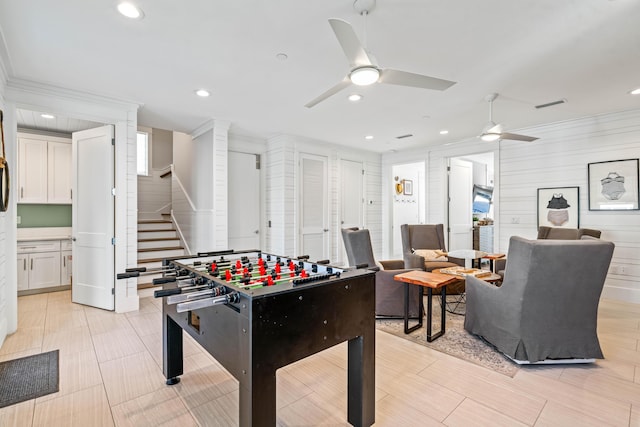 rec room with ceiling fan and crown molding