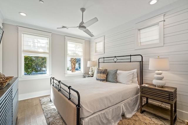 bedroom featuring dark hardwood / wood-style flooring, multiple windows, ceiling fan, and ornamental molding