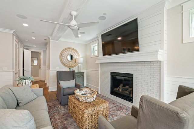 living room with ceiling fan, crown molding, a fireplace, and dark hardwood / wood-style flooring