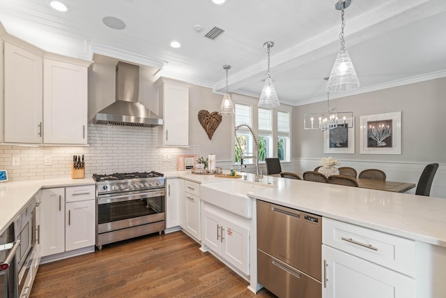 kitchen with white cabinets, decorative light fixtures, wall chimney exhaust hood, and appliances with stainless steel finishes