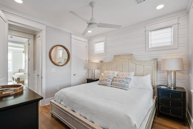 bedroom featuring wood walls, dark hardwood / wood-style floors, ceiling fan, and ornamental molding