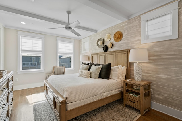 bedroom featuring ornamental molding, ceiling fan, beamed ceiling, and wooden walls